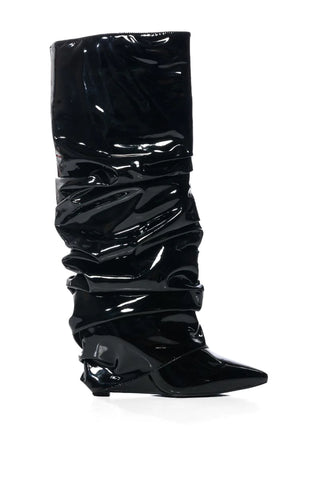 Image of black knee high pointed toe boots made of black patent leather with a wedge heel and scrunched fold over boot silhouette