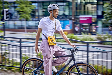 A man on a bicycle in a city wearing a Raleigh cycle helmet