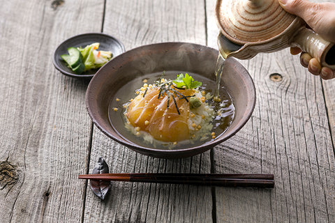 Pour hot rice into a large bowl, place the sea bream in the dipping sauce, sprinkle with bubu arare, chopped nori, and mitsuba, add white sesame seeds and wasabi, and pour tea.