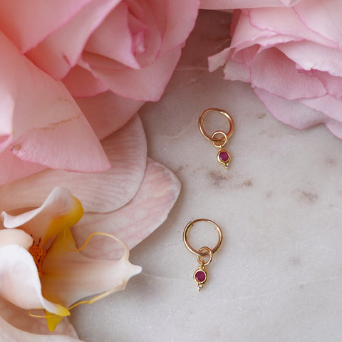 Ruby July Birthstone Hoop earrings on marble with pink orchids and roses