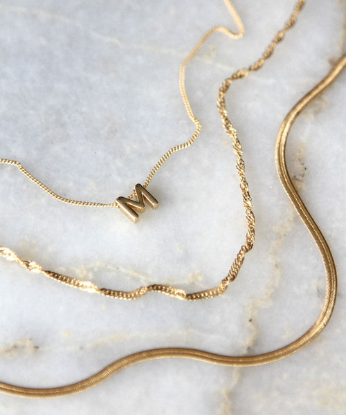 Gold filled necklaces laying on marble.