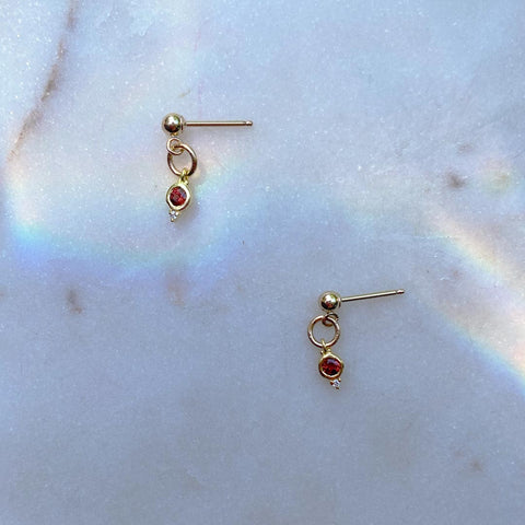 January Garnet Birthstone Stud Earrings on a marble background