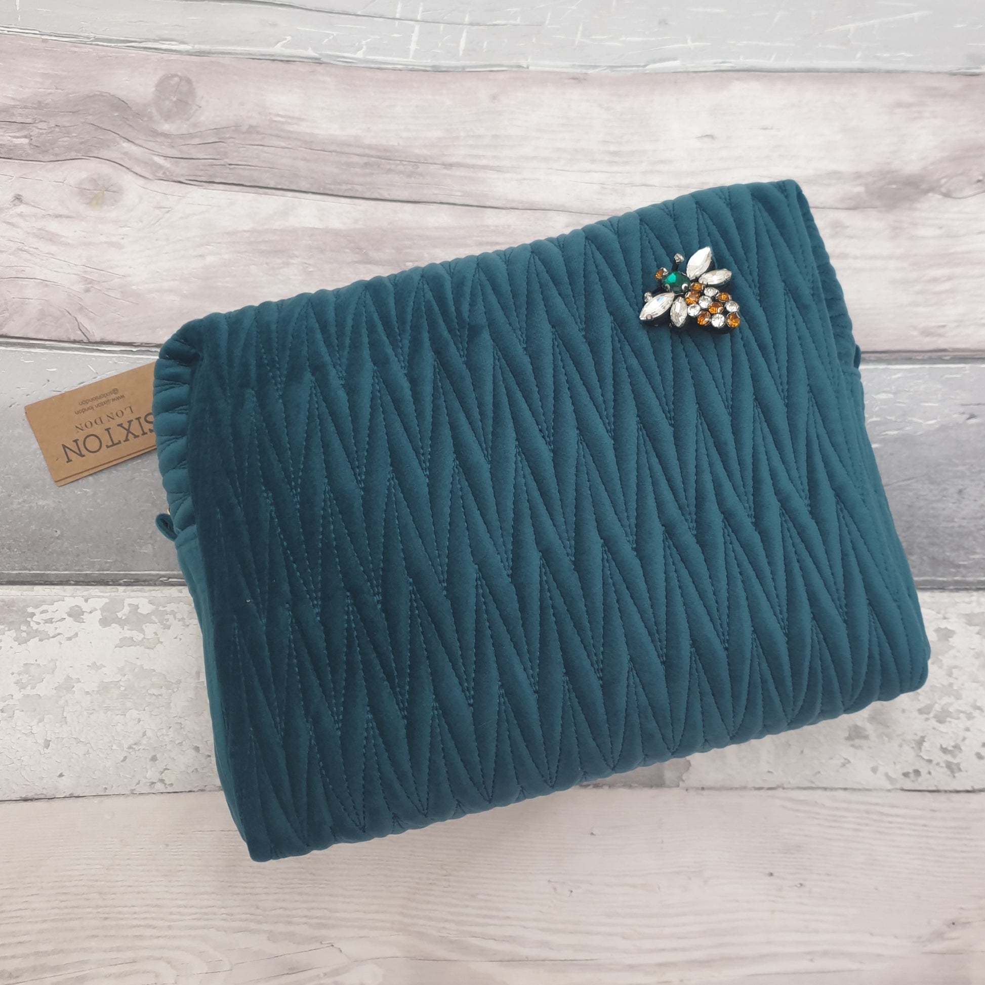 Teal coloured washbag in quilted velvet with a removable Bee Brooch.