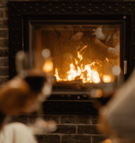 a cozy living room warmed by fire with two individuals holding a wine glass
