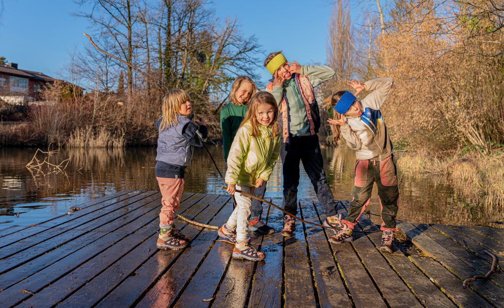 Fünf Kinder stehen auf einem Steg am Wasser