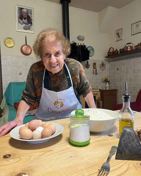 Im Herzen von Sansepolcro, einer Stadt in der Provinz Arezzo, Italien, lebt eine außergewöhnliche Frau namens Natalina Moroni, liebevoll bekannt als Nonna Natalina. Geboren im Jahr 1935, begann ihre Reise in die kulinarische Welt im Alter von 20 Jahren, als sie die Kunst der Teigzubereitung durch die Beobachtung ihrer geliebten Mutter und Schwiegermutter erlernte.  Nonna Natalinas Ruhm erreichte unerwartet im März 2022 seinen Höhepunkt, als ihr Enkel Luca beschloss, ihre Kochkünste auf TikTok zu präsentieren. Kaum zu glauben, dass dies der Beginn eines digitalen Phänomens sein würde, das Nonna Natalina über 3,3 Millionen Anhänger einbrachte und sie zu einem authentischen Symbol der Echtheit machte.  Nonna Natalinas kulinarische Geschichte:  Alles begann in der bescheidenen Küche von Nonna Natalina, wo der berauschende Duft von handgemachter Pasta durch die Luft schwebte. Mit einem Funkeln in den Augen teilte sie die Geschichte ihrer Teigzubereitung. "Ich habe es gelernt, indem ich meiner Mutter und Schwiegermutter zugesehen habe", erinnerte sie sich. Ihre Hände kneteten den Teig geschickt, als wäre es ihr zweite Natur.  Mit dem Entfalten ihrer kulinarischen Abenteuer in den sozialen Medien waren die Reaktionen überwältigend. Nonna Natalina wurde nicht nur zur geliebten Großmutter für ihre Familie, sondern für die ganze Stadt. "Die Leute sind sehr glücklich; sie sind sehr glücklich mit mir. Ich freue mich sehr, die Großmutter für alle geworden zu sein", teilte sie mit, ein echtes Lächeln erhellte ihr Gesicht.  Das Geheimnis ihres perfekten Pastateigs? "Den Teig oft kneten und ein wenig Öl hinzufügen", verriet sie. Nonna Natalinas Lieblingspasta zum Zubereiten? "Ich mache wirklich gerne Ravioli", sagte sie. Ihre Augen spiegelten die Freude wider, jedes zarte Stück zu gestalten.  Nonna Natalina, die 89-jährige Pastasensation aus Sansepolcro  Mit einem Hauch von Nostalgie teilte Nonna Natalina ihre liebste Erinnerung an Pasta. "Ich erinnere mich sehr gut an meine Familie. Als ich klein war, hatte ich 8 Brüder, und frische Pasta wurde immer an Feiertagen gegessen. Pasta erinnert mich an meine Familie." Ihre Inspiration? "Meine Lehrer waren meine Mutter und meine Schwiegermutter", erklärte sie dankbar.  Als wir tiefer in ihr Leben eintauchten, äußerte Nonna Natalina einen Wunsch. "Ich wünschte, ich könnte noch einmal die Welt bereisen. Ich habe viele Reisen in meinem Leben gemacht; ich mag es wirklich zu reisen und verschiedene Länder und Städte kennenzulernen."  Nonna Natalinas Abschiedsworte hallten im Wesen ihrer Existenz wider. "Die Bedeutung, die eigenen Großeltern zu lieben. Ich freue mich sehr, eine Familie zu haben, die mich liebt. Was ich allen vermitteln möchte, ist, weiterhin Essen zu Hause mit den eigenen Händen zu machen, vor allem."  Fazit:  In Nonna Natalinas Küche erzählt jede Pastaschnur eine Geschichte von Tradition, Liebe und der zeitlosen Freude an hausgemachten Mahlzeiten. Während sie weiterhin mit ihrer kulinarischen Kunst inspiriert, hinterlässt Nonna Natalina eine unauslöschliche Spur - ein Erbe, das nicht nur Generationen, sondern auch die digitalen Sphären überdauert und uns alle an die Schönheit der Einfachheit eines gut gemachten Gerichts und der Verbundenheit am Esstisch erinnert.