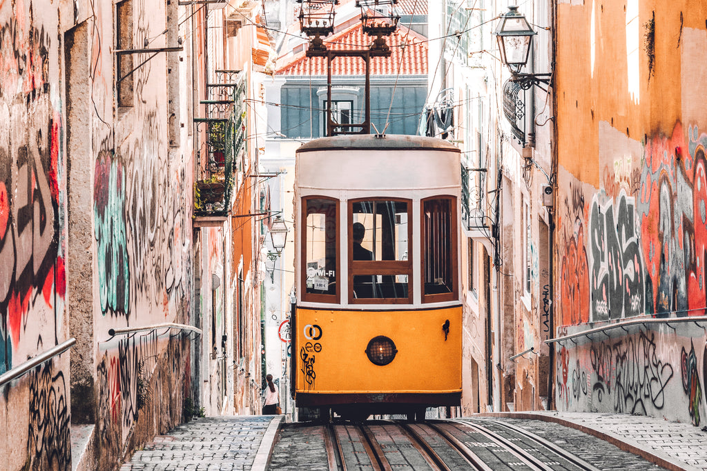 Iconic Lisbon yellow tram passing by colorful buildings in the city.