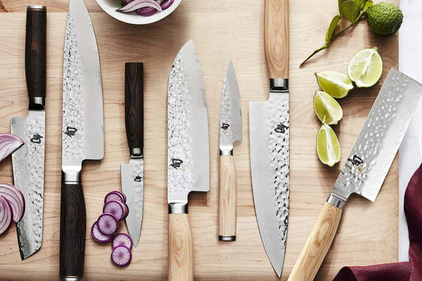 A variety of Shun knives on a cutting board with veggies.