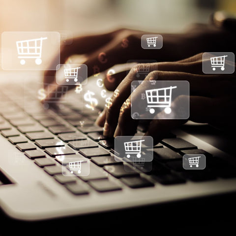 Person typing on a laptop keyboard with shopping cart icons across the image.