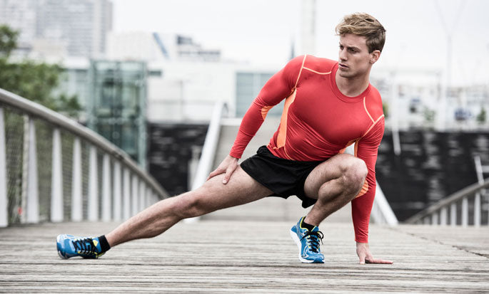 Supple Instant male runner in red shirt in city on bridge stretching. Tip: Stretching muscles help joint pain.