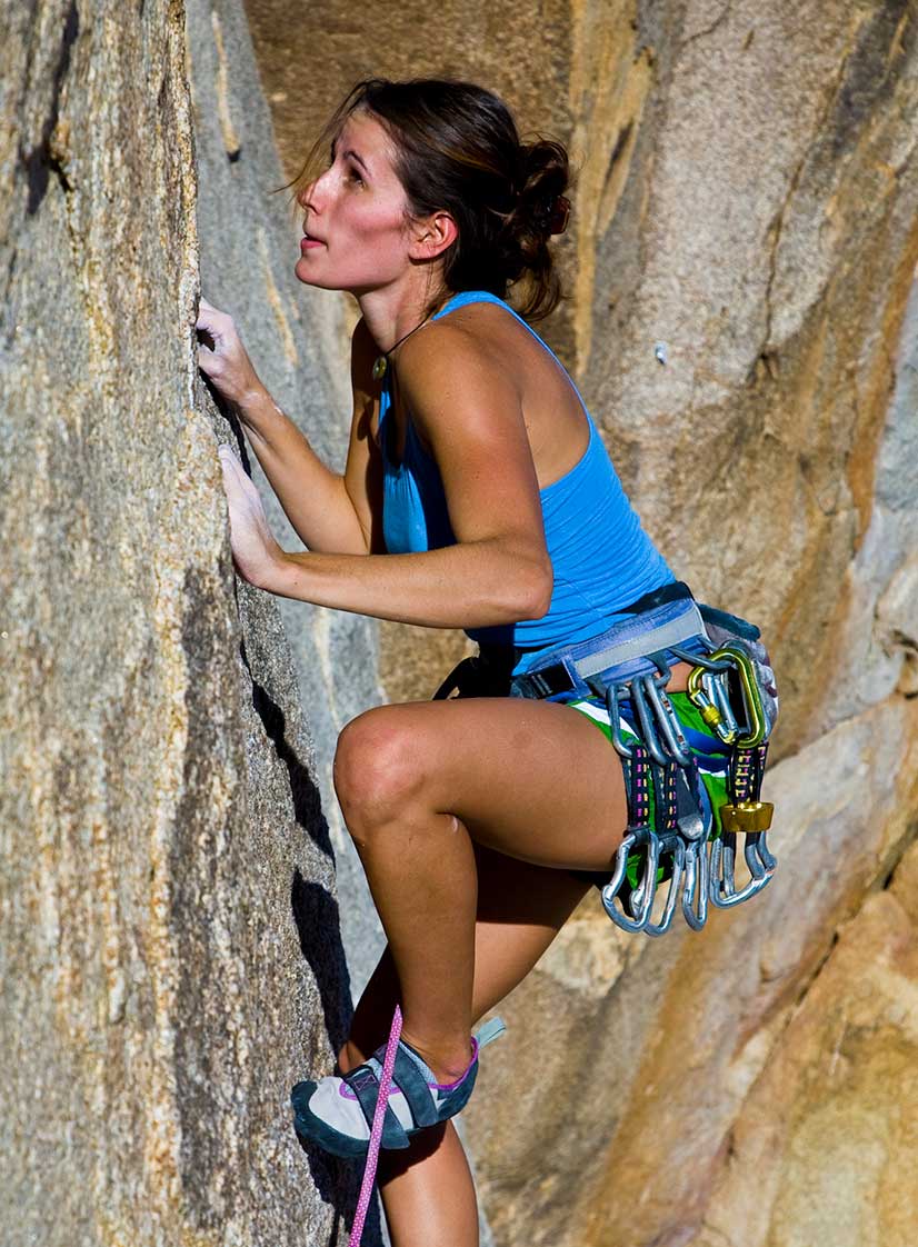 Woman rock climbing outdoors in shorts using a rope. Supple Drink with chondroitin. Tip: strong muscles help with hand pain.