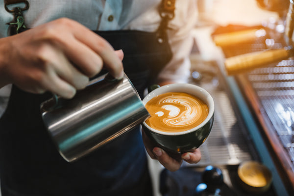 Ein Barista bereitet einen schaumigen Cappuccino zu - eines der beliebtesten Getränke, um dich aufzuwecken.