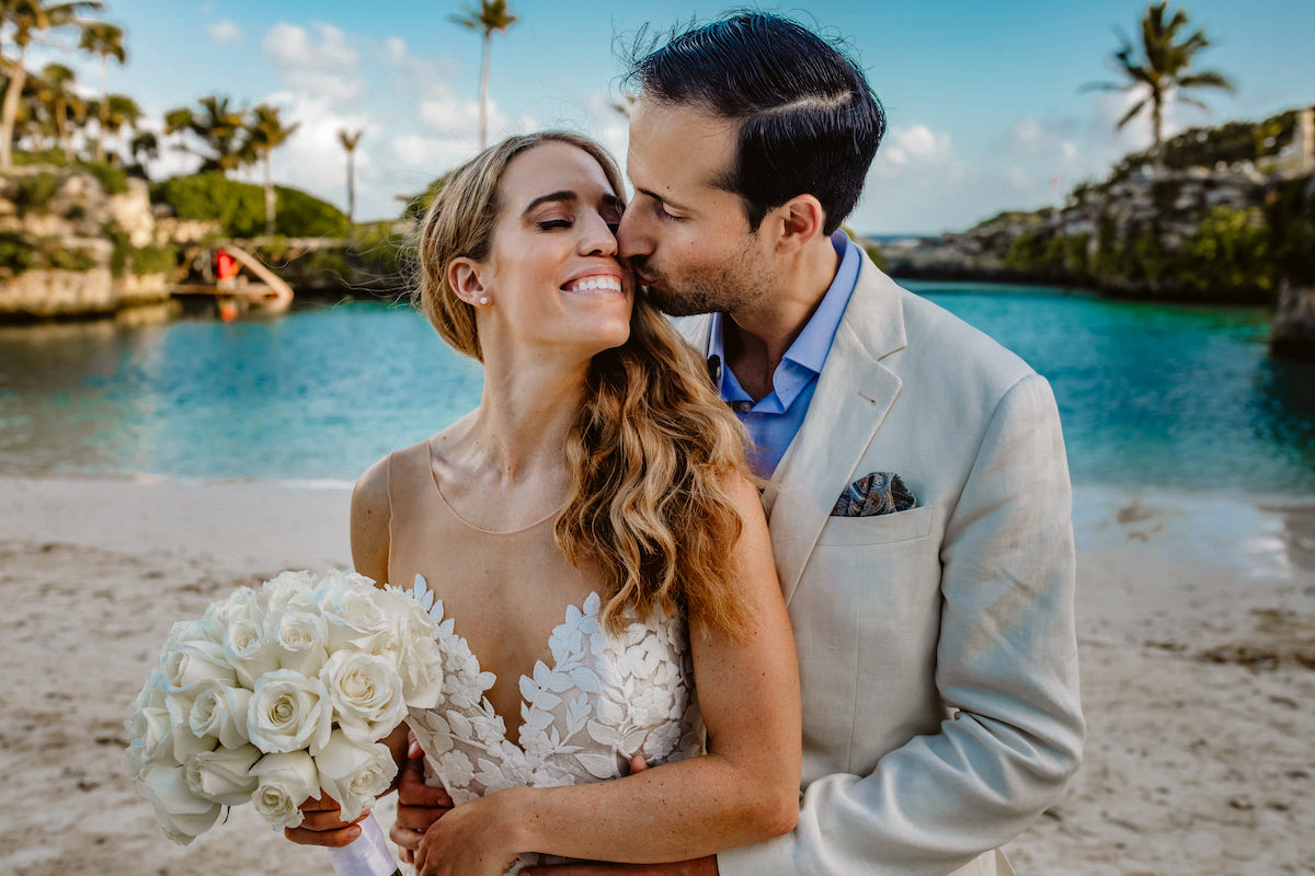 Groom kissing bride with lagoon background