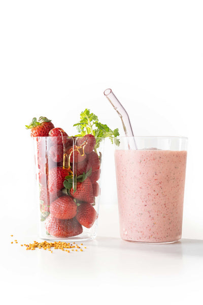 Strawberry mint smoothie next to a cup of strawberries.