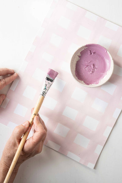 Placemat being painted with a pink gingham pattern.