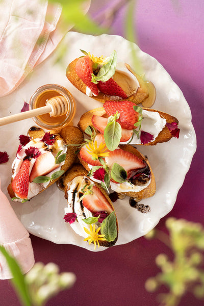 Strawberry goat cheese crostini on a white plate with flowers.