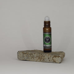A tube of roll-on fragrance oil being displayed on a tan stone