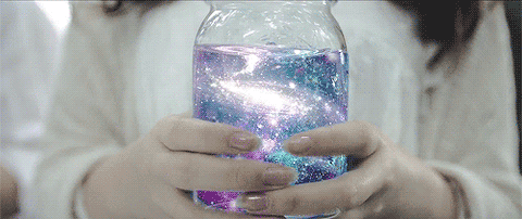 A person holding a jar with a swirling galaxy in it