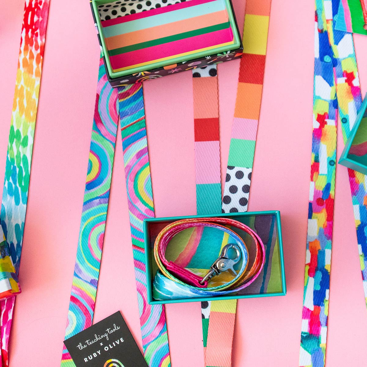 Colourful Ruby Olive lanyards laying on pink background