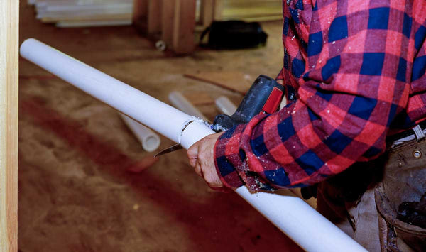 plumber cutting white pvc pipe with a saw