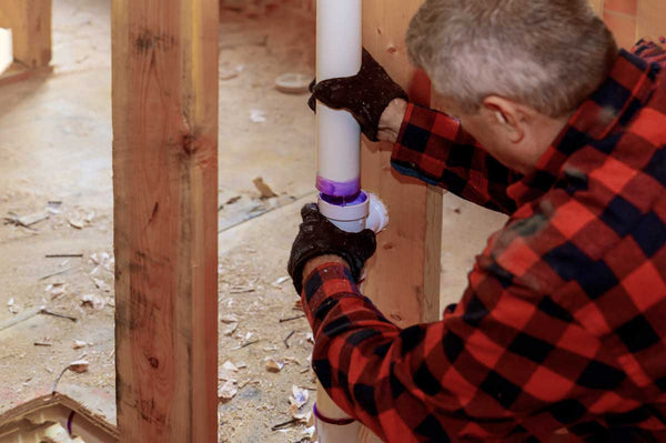plumber using pvc cement glue to connect two pieces of pvc pipe
