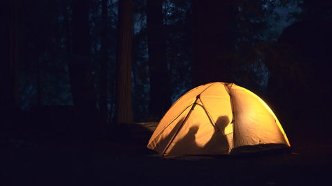 A TETON Sports Vista Tent is lit from within at night showing the silhouettes of two people.