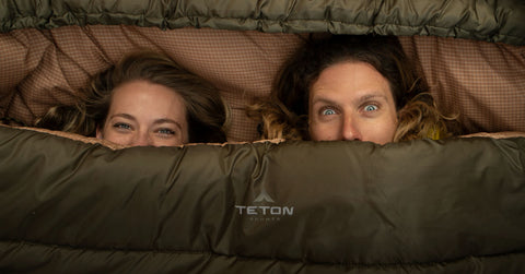 Two women peek out from inside a TETON Sports Mammoth Sleeping Bag.