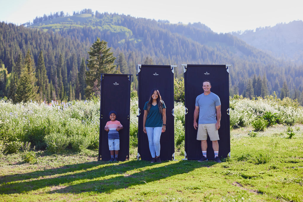 Family stands in front of cots in field to show 3 sizes.