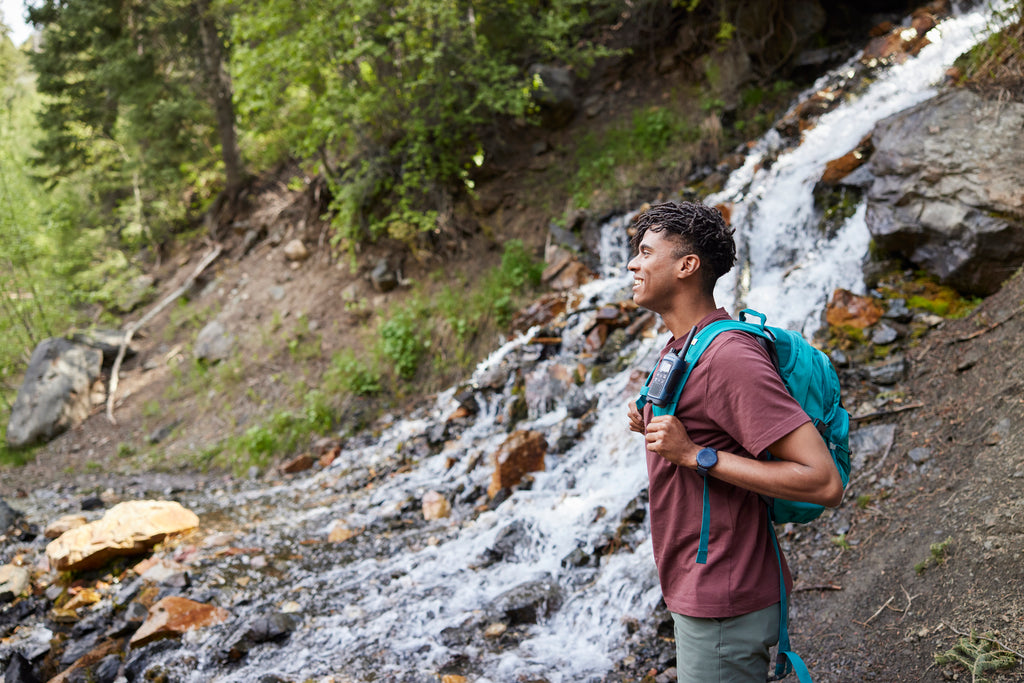 Man looks out over waterfall with backpack on.