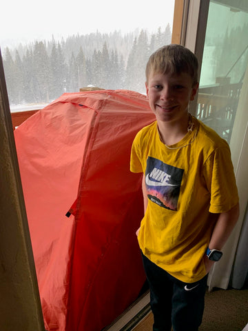 A young boy stands in front of his TETON Sports Mountain Ultra Tent.