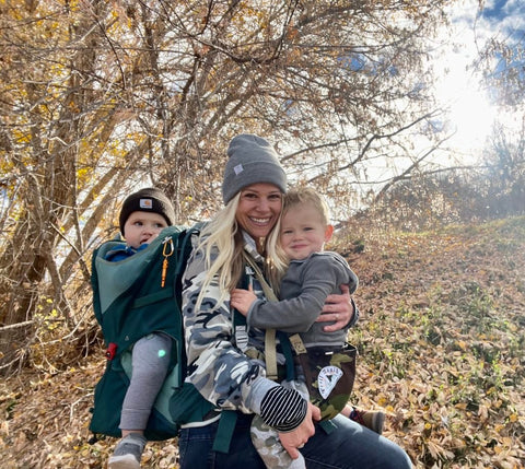 A mother with two young children hiking in the woods in autumn.