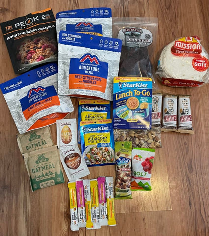 A group of great hiking & backpacking foods laying together on a hardwood floor.