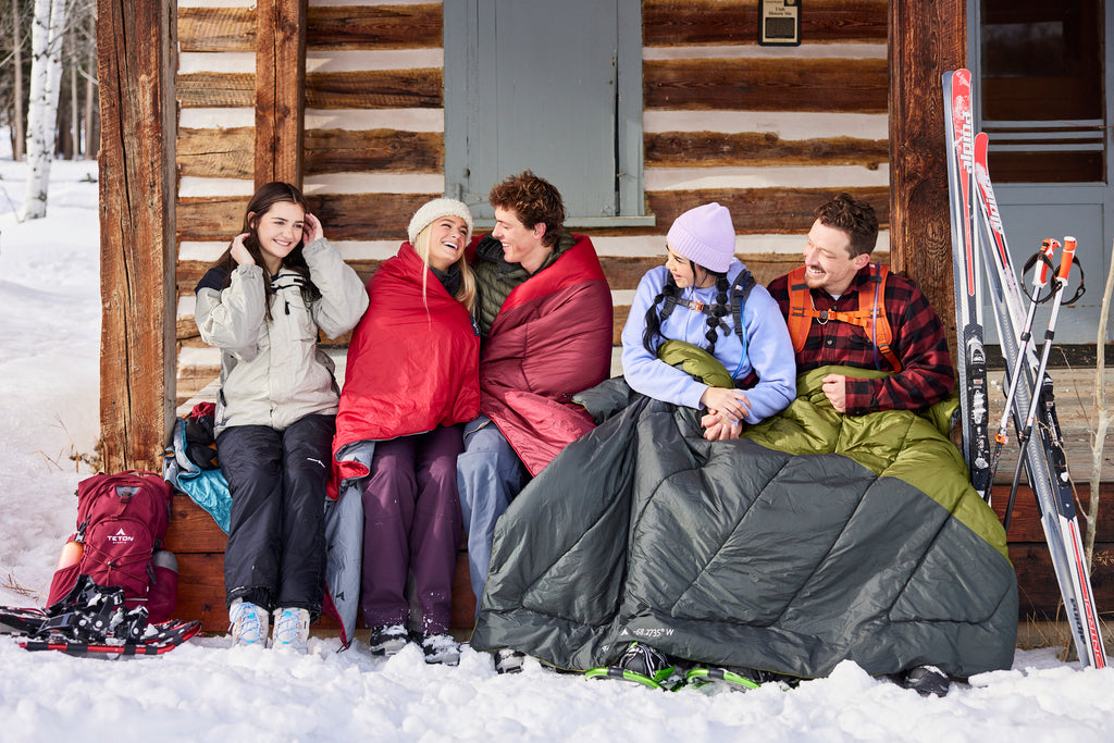 Friends sit together on porch in winter with camp blankets.