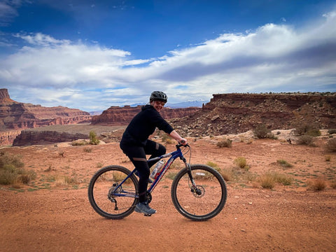 A biker surrounded by red, rocky canyons and mountains.