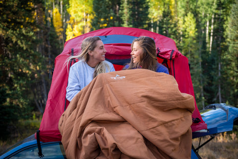 Two women snuggled up in a TETON Sports canvas mammoth sleeping bag.