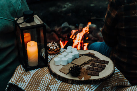 The makings of S'mores on a plate near a campfire.