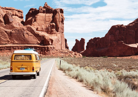 A Volkswagen van traveling through red rocky mountains.