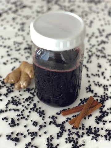 elderberry syrup in a jar surrounded by elderberries