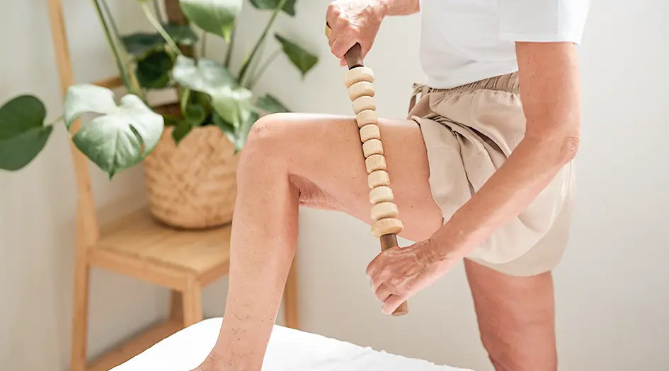 Eine Frau wendet den Faszienstab von styleholz für die Massage der Oberschenkel an.