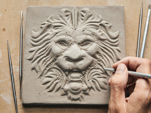 sculptor carving a lion tile in relief