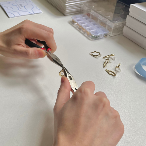 Photo présentant la réalisation à la main d'une paire de boucles d'oreilles