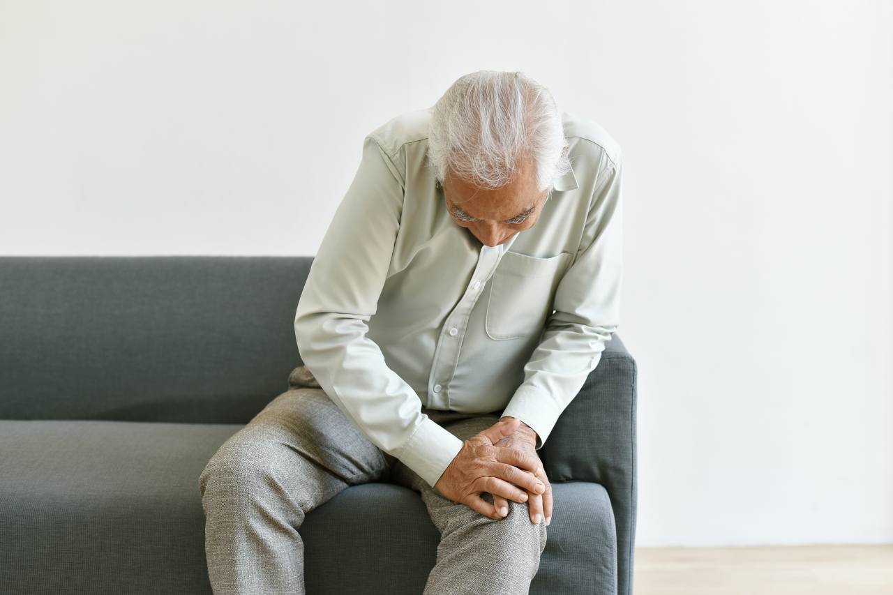 Arthritis joint pain problem in old man, elderly man with hand on knee