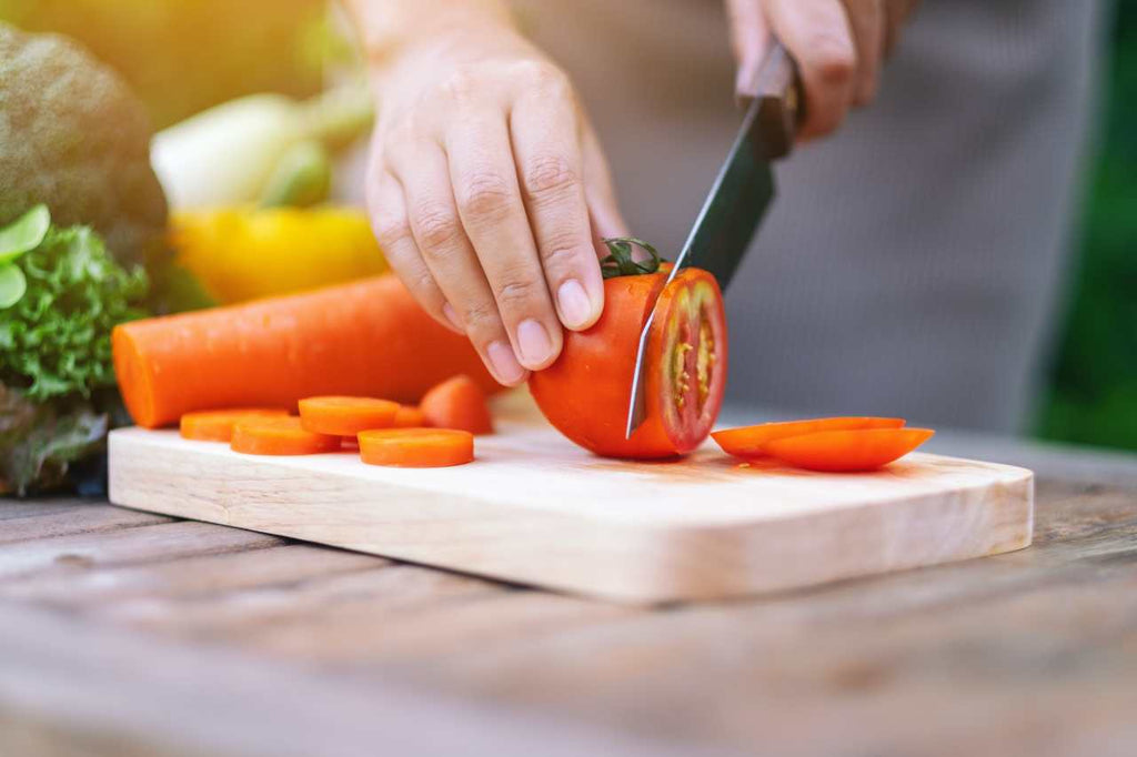  cutting and chopping tomato by knife on wooden board