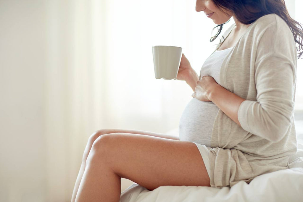 close up of pregnant woman holding a mug of bone broth
