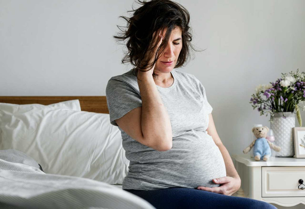 Pregnant woman on bed with morning sickness