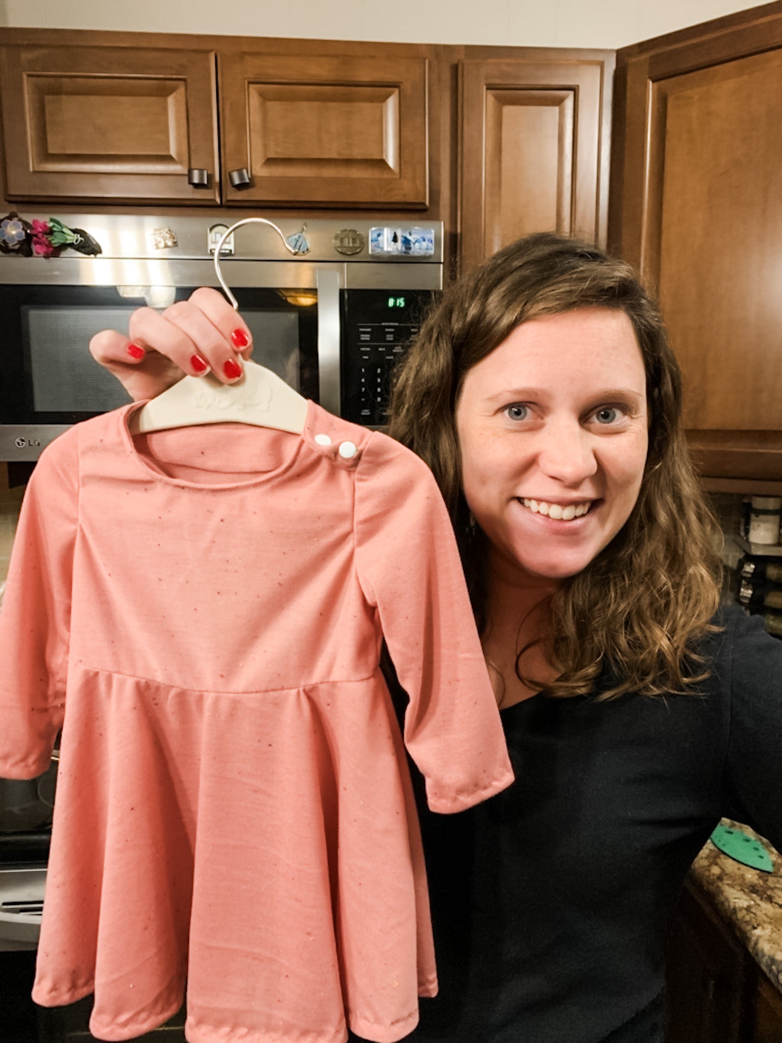 Casey Chatham holding a dress on a hanger made using the Ingrid dress pattern from Oh Me Oh My Sewing