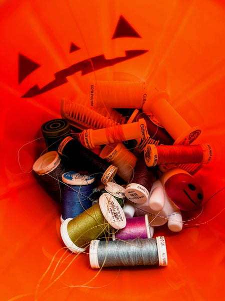Pippa's halloween bucket filled with spools of thread in a tangle