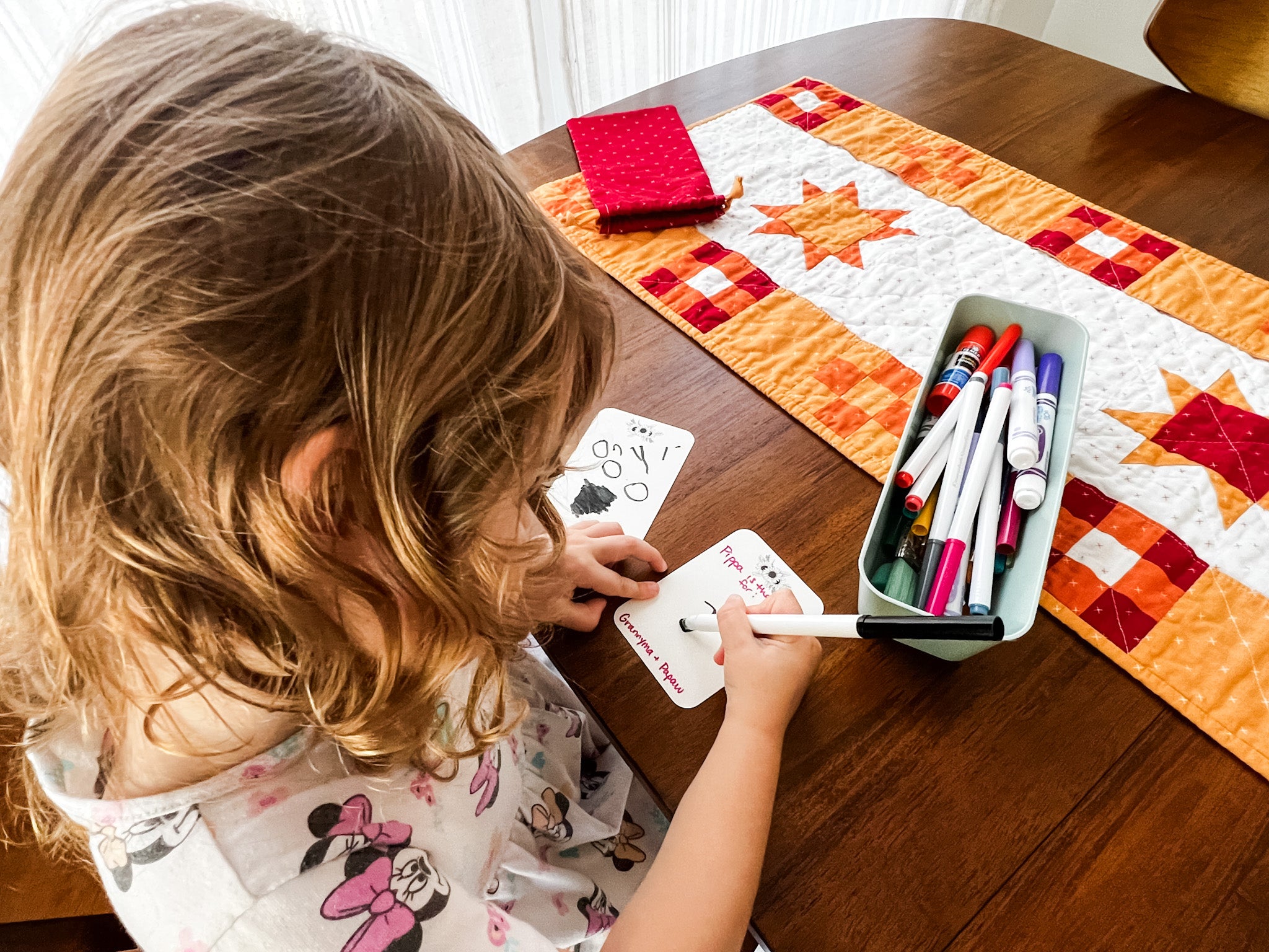 pippa, 3, drawing on a blank gratitude journaling card for the pockets full of blessings quilted table runner