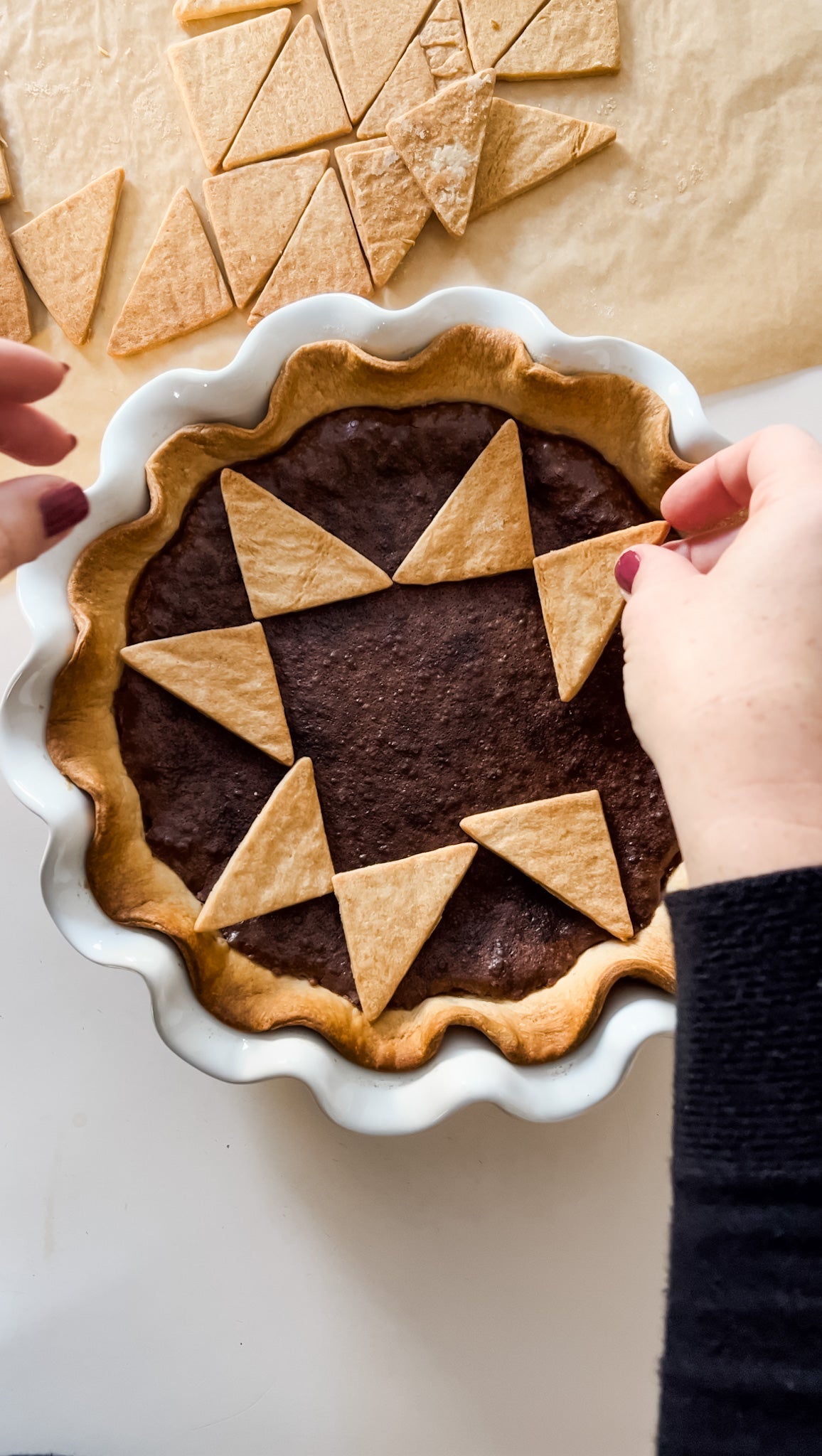 arranging triangles of pie crust on top of a fudge pie to make a quilted pie