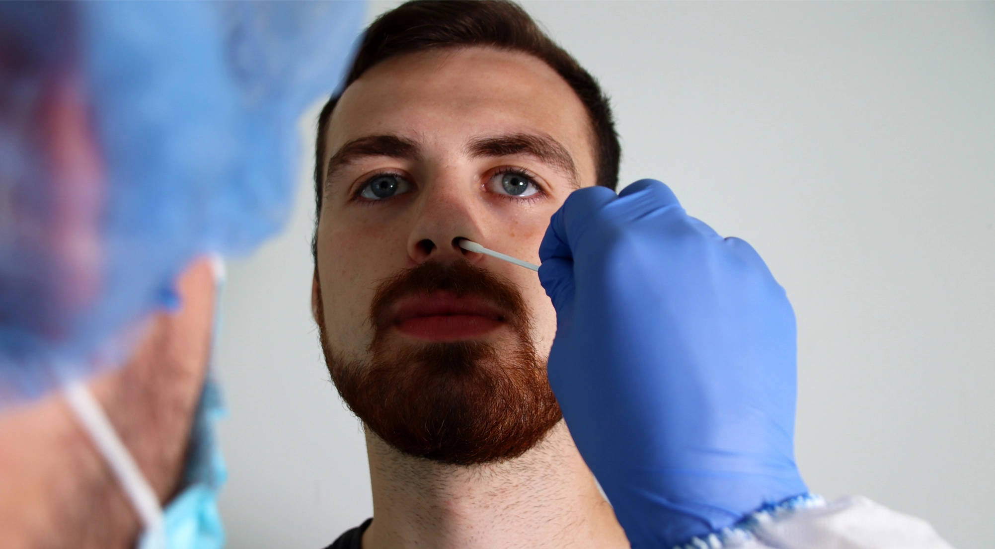 A medical professional performing a nasal swab covid test on a man.